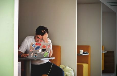 Man seated at a table typing on a laptop